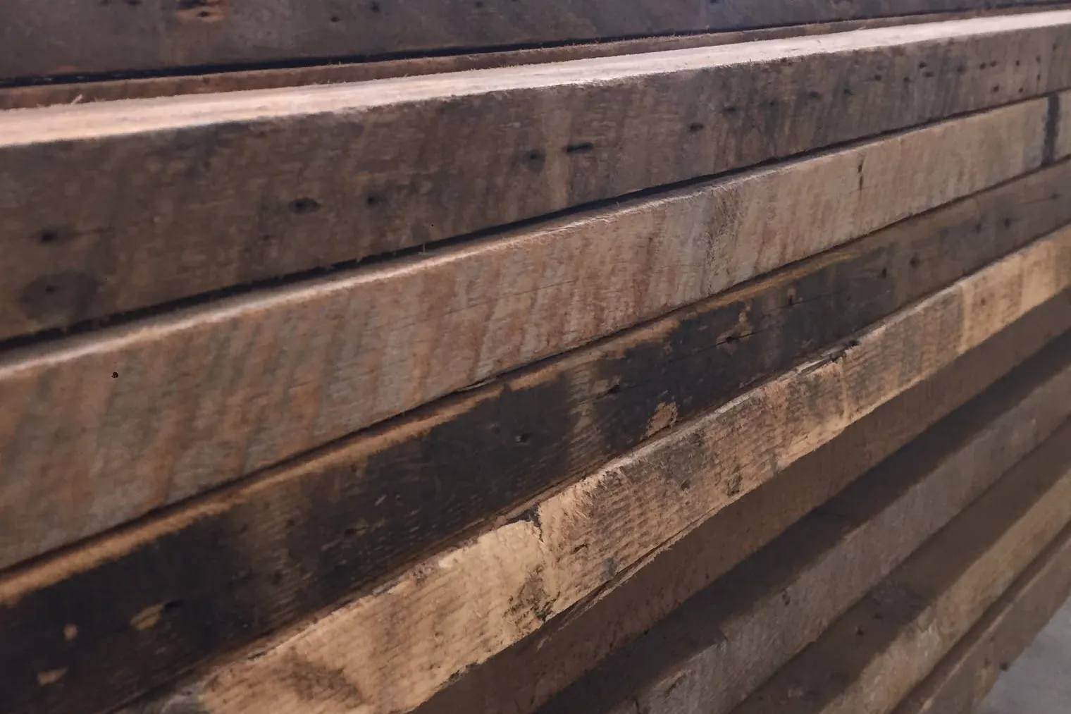 Reclaimed timbers stacked in the shop, nail and bolt holes still in them