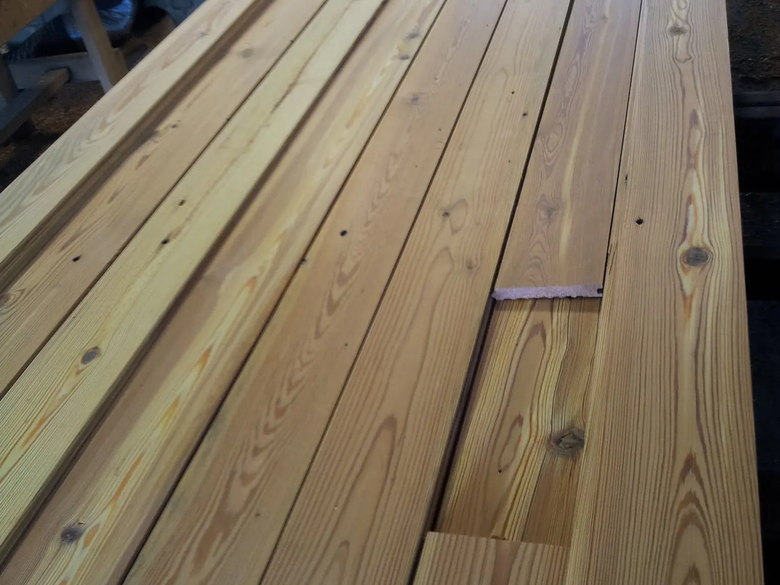 Long antique pine boards, milled and stacked, showing their tight grain