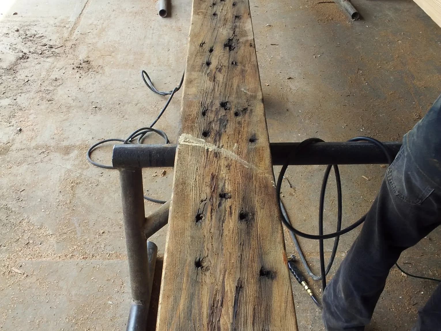 A reclaimed timber on the rack, full of old nail and bolt holes
