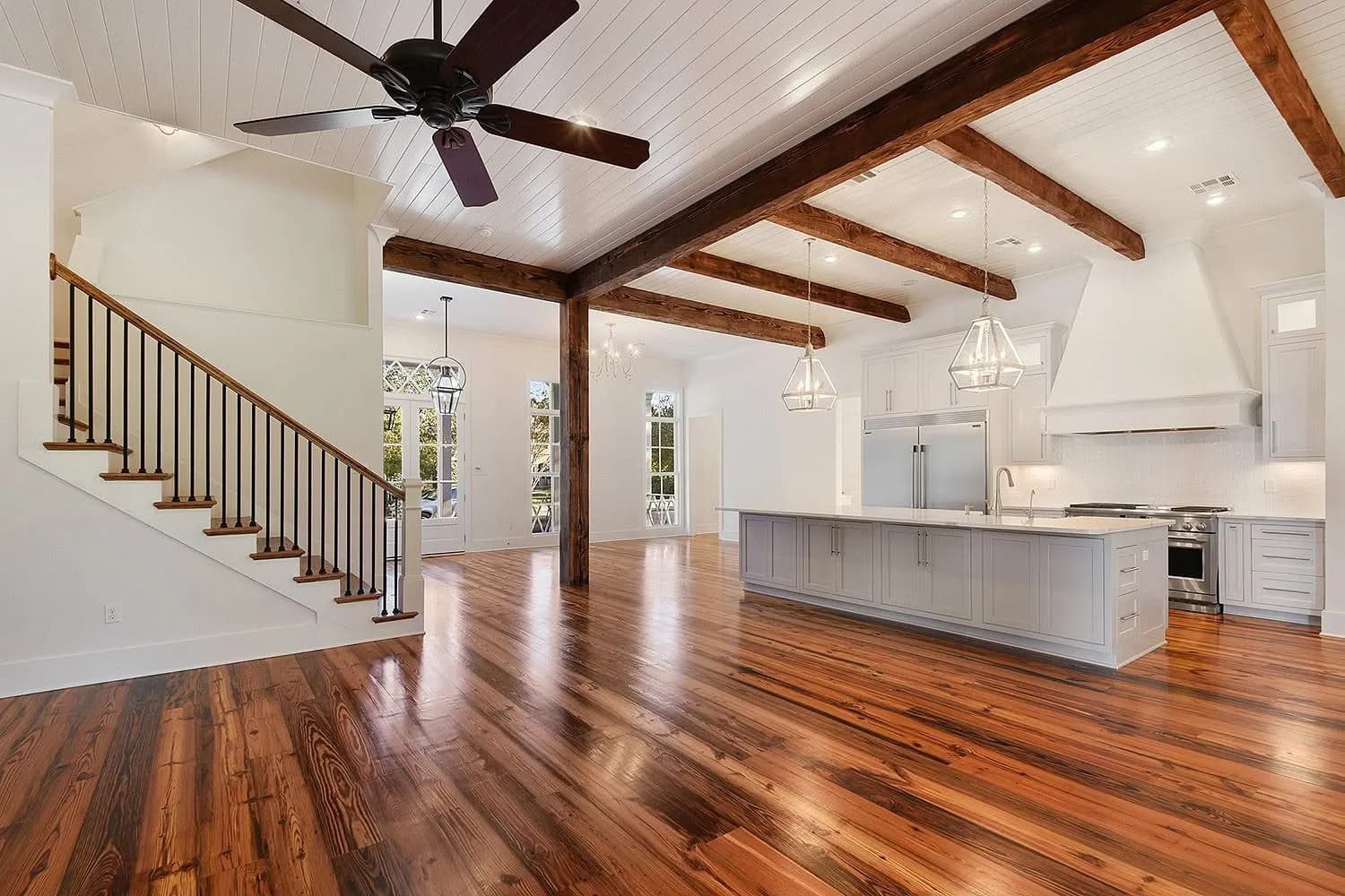 An open great room with reclaimed ceiling beams over a wide-plank floor