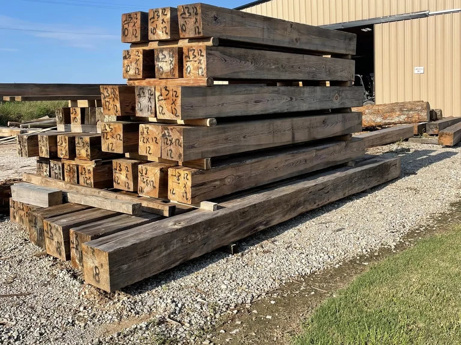 Beams stacked in the yard beside the mill buildings on Industrial Boulevard